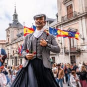Grupo de estudiantes disfrutando del ambiente festivo de San Isidro en Madrid entre música, luces y puestos tradicionales.