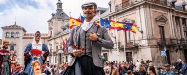 Grupo de estudiantes disfrutando del ambiente festivo de San Isidro en Madrid entre música, luces y puestos tradicionales.