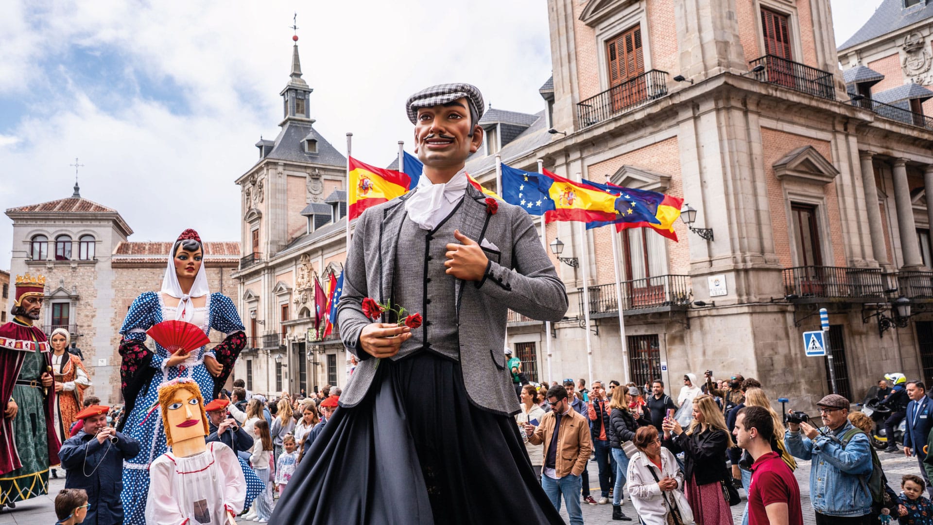 Grupo de estudiantes disfrutando del ambiente festivo de San Isidro en Madrid entre música, luces y puestos tradicionales.